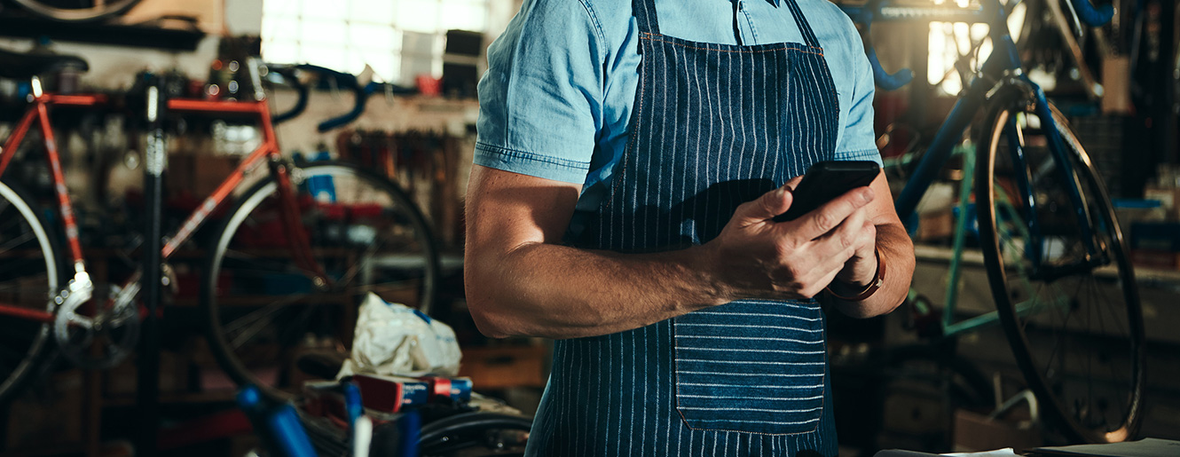 Man working in a mike shop on a smartphone